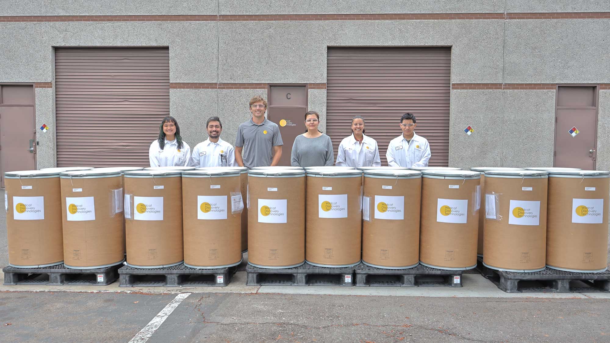 Wildcat team members proudly standing behind the 1 MT LFP barrels.